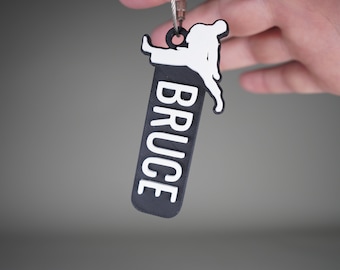 May include: Black and white keychain with a silhouette of a person kicking, and the name "BRUCE" written vertically in white letters.
