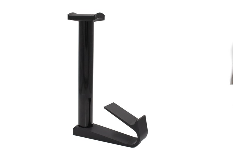 May include: Black plastic stand with a vertical post and a curved hook at the bottom. The stand is designed to hold a variety of items.