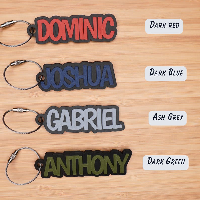 May include: Four personalized keychains with names DOMINIC, JOSHUA, GABRIEL, and ANTHONY in different colors. The keychains are dark red, dark blue, ash grey, and dark green.