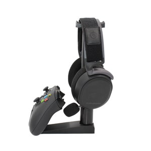 May include: A black gaming headset with a microphone and a black controller stand on a white background.