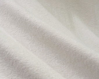 May include: Close-up of a white, textured fabric with a soft, smooth feel. The fabric is folded and draped, showing its natural wrinkles and folds.