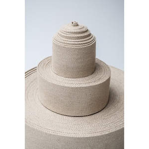 May include: A stack of beige cotton webbing rolls, each roll is a different width, the rolls are stacked in a pyramid shape.