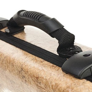 May include: A tan-colored case with a black zipper and a black handle. The handle is made of a textured rubber material and has a black strap.