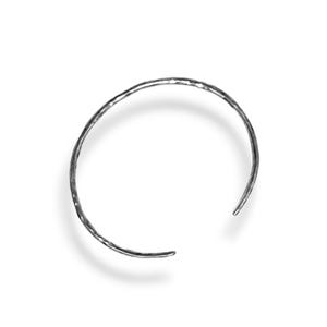Könnte beinhalten: Ein silbernes, gehämmertes Armkettchen mit einem einfachen, offenen Design.