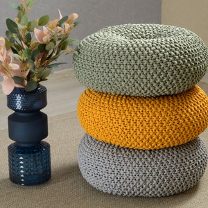 May include: Three round knitted poufs stacked on top of each other. The top pouf is light green, the middle pouf is yellow, and the bottom pouf is gray.