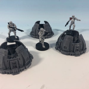 May include: Four gray plastic miniature bases with a raised design, each with a white plastic miniature figurine standing on top. The figurines are wearing white armor and holding weapons.