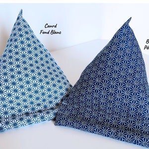May include: Two triangular fabric stands for mobile devices, featuring a geometric star pattern. The left stand is white with blue lines labeled Canrd Fond Blanc, and the right stand is blue with white lines labeled Bleu P&eacute;trole.