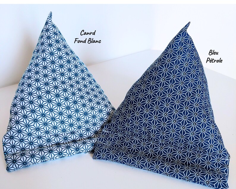 May include: Two triangular fabric stands for mobile devices, featuring a geometric star pattern. The left stand is white with blue lines labeled Canrd Fond Blanc, and the right stand is blue with white lines labeled Bleu P&eacute;trole.