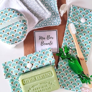 May include: A beauty gift set featuring a bar of Citron Verveine soap, a bamboo toothbrush, reusable fabric facial rounds, and two fabric pouches with a teal and white fan pattern. A card labeled Ma Box Beauté is included in the collection.