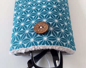 May include: Teal and white geometric patterned glasses case with a wooden button closure. The case has a soft, grey trim and holds a pair of black-framed glasses. The case is designed to protect eyeglasses.