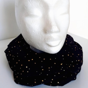 May include: A black velvet collar with gold metallic polka dots. The collar is displayed on a white mannequin head. The collar has a scalloped edge and is designed to be worn around the neck.