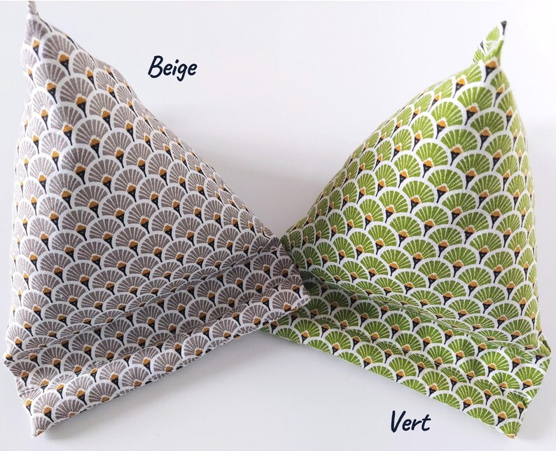 May include: Two fabric book pillows, one beige and one green, are displayed. The beige pillow has a repeating pattern of gray, white, and gold fan shapes. The green pillow has a similar pattern in shades of green and white. The word "Beige" is written on the beige pillow and the word "Vert" is written on the green pillow.