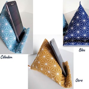 May include: Triangle-shaped fabric phone stands in blue, navy, and ochre, each with a white geometric pattern. A smartphone rests in each stand, showcasing the product's functionality. The stands are labeled "Bleu C&eacute;ladon", "Bleu", and "Ocre".