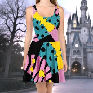 A colorful, patterned dress with a mix of polka dots, stripes, and other geometric shapes in various colors, including pink, yellow, and blue. The dress appears to be a short, sleeveless style. In the background, there is a castle or palace-like structure, which adds a sense of fantasy or fairy tale-like atmosphere to the scene.