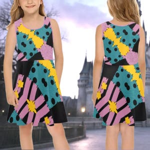 A young girl wearing a colorful, patterned dress with a mix of pink, yellow, black, and blue colors.