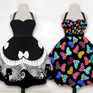 May include: Two aprons on mannequins. The left apron is black with white pinstripes, a white bow, and a bottom panel featuring a gray skull pattern and a black silhouette of a hill and trees. The right apron is black with colorful polka-dot bows.