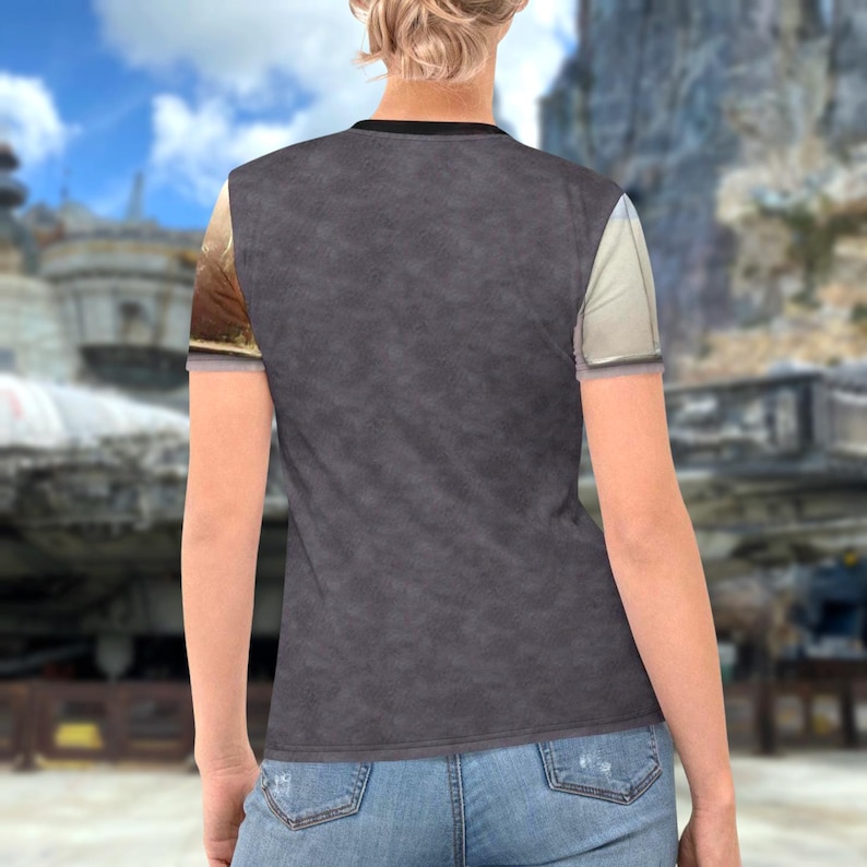 a person wearing a gray t-shirt with a graphic design on the left side, standing in front of a cityscape with buildings and a bridge in the background.