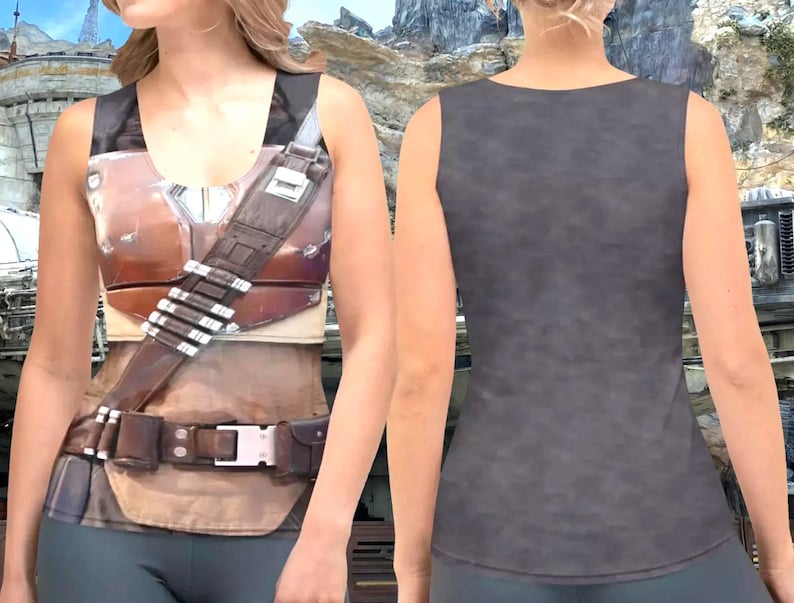 A woman wearing a tank top with a detailed design, including a belt and straps, against a rocky landscape background.