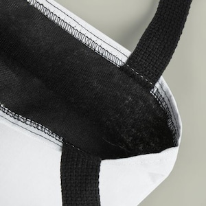 A close-up view of a black and white tote bag with a black strap and a white interior.