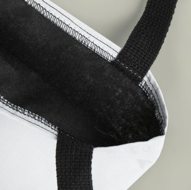 A close-up view of a black and white tote bag with a black strap and a white interior.