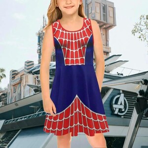 A young girl wearing a Spiderman-themed dress with a red and blue color scheme and a spider web pattern.