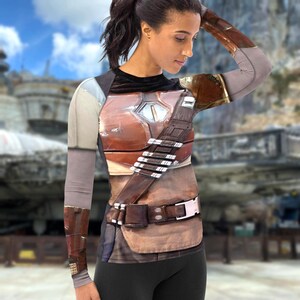 A woman wearing a costume with a metallic, futuristic design, including a chest plate and a belt with buckles.