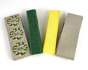 May include: Four rolls of wired ribbon. One roll is beige with a repeating pattern of lemon wreaths and the word Hello in black script. The second roll is solid dark green, the third is solid bright yellow, and the fourth is solid light beige.