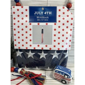 May include: A patriotic windsock, 48 inches (121.9 cm) long, with a red, white, and blue star and stripe design. The packaging reads "July 4th". The bottom of the packaging has a navy blue section with white star embroidery.