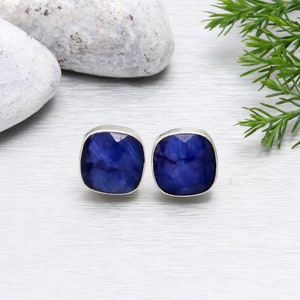 Op de afbeelding: Een paar zilveren oorbel studs met vierkante blauwe edelsteen inslagen. De edelstenen hebben een marmerpatroon.