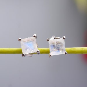 May include: A pair of silver earrings with square-shaped moonstone gemstones. The earrings have a simple design and are perfect for everyday wear.