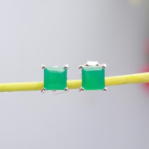 May include: A pair of silver stud earrings with square green gemstones.