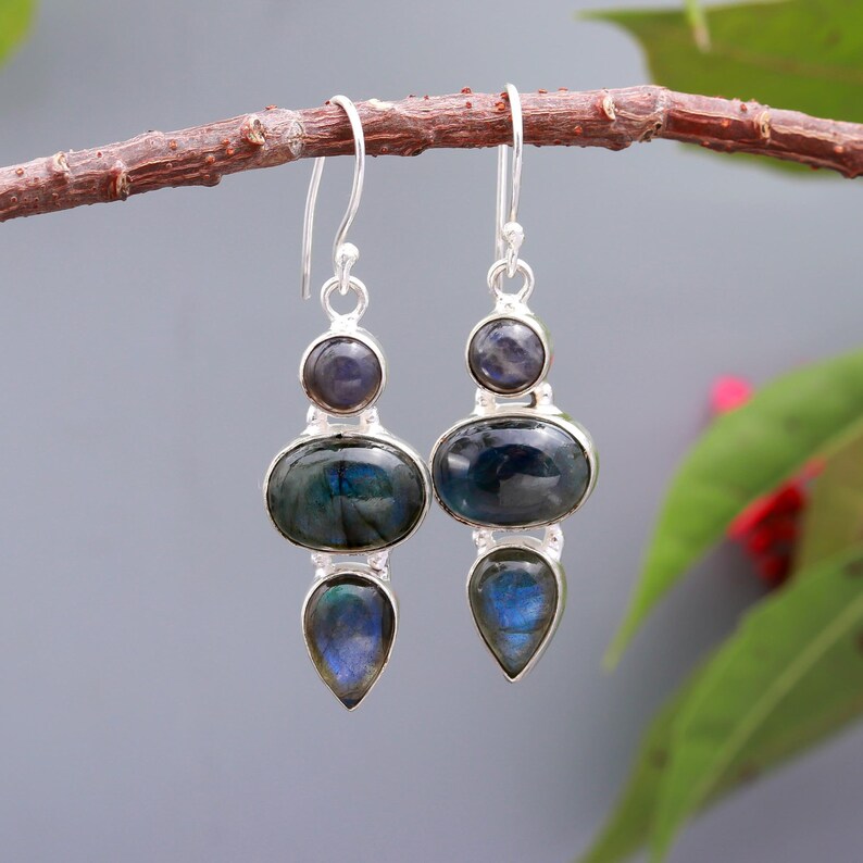 May include: A pair of silver dangle earrings with three iridescent blue labradorite stones on each earring.