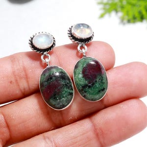 Peut inclure: Une paire de boucles d'oreilles en argent avec des gouttes de pierres précieuses vertes et rouges et des accents de pierre de lune blanche.