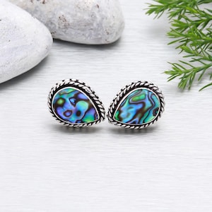 Könnte beinhalten: Ein Paar silberne tropfenförmige Ohrringe mit einem blauen, grünen und schwarzen Abalone-Muscheleinlege.