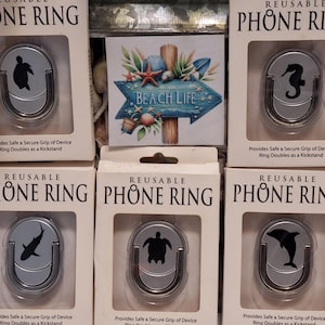 May include: Six reusable phone rings in boxes, each with a silver ring and a black sea creature design: a turtle, seahorse, shark, turtle, and dolphin. The boxes read "PHONE RING" and "BEACH LIFE".