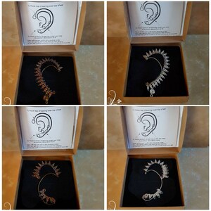 May include: Four open boxes with instructions on how to wear an ear cuff. Each box contains a silver or gold ear cuff with a decorative design. The ear cuffs are made of metal and have a hook at the top to secure them to the ear.