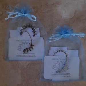 May include: Two small blue organza bags with silver ear cuffs inside. Each bag has a white card with the text "Magical Enchantments" and contact information for the seller.