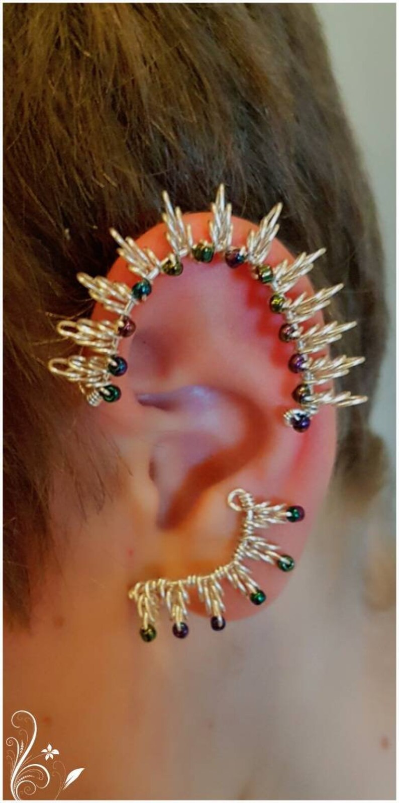 May include: A silver ear cuff with a spiky design and iridescent green and purple beads.