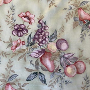 May include: Fabric with a repeating pattern of watercolor-style fruits and flowers. The design features pink pears, purple grapes, and pink and purple flowers with green and brown leaves on a light green background.