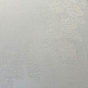 May include: A white tablecloth featuring a subtle, tone-on-tone damask pattern of grape clusters and vine leaves. The fabric has a smooth, woven texture with the intricate botanical design visible across the surface in a monochromatic white finish.