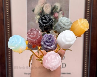 Könnte beinhalten: Ein Strauß geschnitzter Edelsteinrosen in verschiedenen Farben, darunter Schwarz, Weiß, Rosa, Lila, Gelb und Blau. Die Rosen sind auf einem goldfarbenen Metallstiel befestigt. Im Hintergrund befindet sich ein gerahmtes Bild.