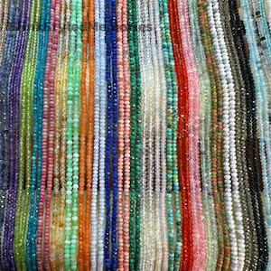 May include: A variety of gemstone beads in different colors and shapes, including amethyst, citrine, emerald, lapis lazuli, malachite, rose quartz, and turquoise. The beads are strung on thin cords and are arranged in rows.