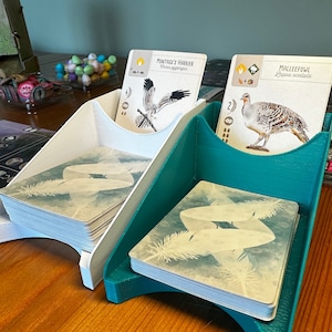 Könnte beinhalten: Zwei teal- und weiße Kartenhalter mit Kartendecks darin. Die oberste Karte jedes Decks zeigt eine Vogelillustration mit dem Text "Mallee­fowl, Leipoa ocellata" und "Montagu's Harrier, Circus pygargus".