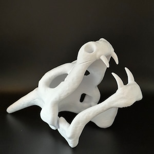 May include: White 3D printed model of a snake skull with its jaw open. The skull is detailed with teeth and bone structure.