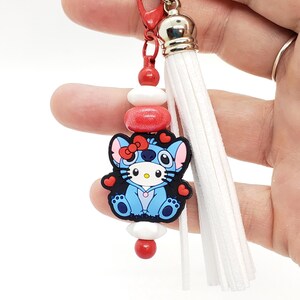 May include: A blue and white cartoon character keychain with red hearts, red and white beads, and a white tassel.