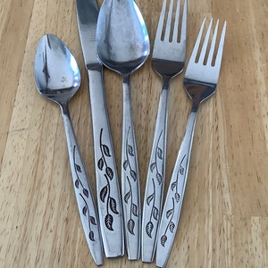 Puede incluir: Cinco piezas de cubiertos plateados con diseños de hojas. El juego incluye un cuchillo para mantequilla, dos cucharas y dos tenedores.