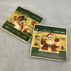 May include: Two vintage-style Christmas-themed coasters. One features a snowman with the text "Holiday Snowman Back in the Day." The other depicts Santa Claus with "Santa's Christmas Candy Canes" and "Peppermint Flavor" text.