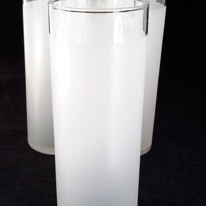 May include: Set of six frosted glass tumblers. The glasses are tall and cylindrical with a slightly rounded bottom. They are made of clear glass that has been frosted to give them a white, opaque appearance.