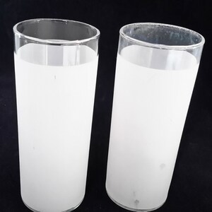 May include: Two frosted glass tumblers with a white frosted finish. The glasses are clear and cylindrical in shape.