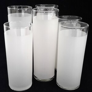 May include: Six frosted glass tumblers, all white, with a slightly rounded shape. The glasses are arranged in a row, with the front three slightly overlapping the back three.